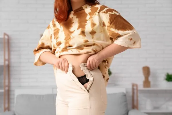 Image of woman trying to do her trousers up after pregnancy weight gain Chesterfield